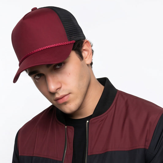 Person wearing a maroon and black trucker cap with cord and jacket on a white background