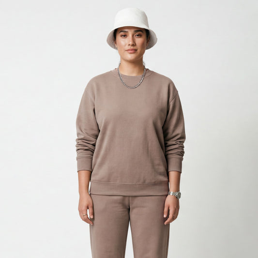 Person wearing a beige sweatshirt and pants with a white bucket hat on a light gray background