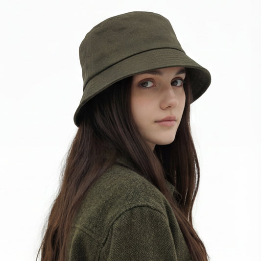 Woman wearing an olive green bucket hat and coat on a white background