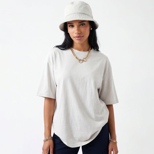 Woman wearing a white oversized t-shirt and beige bucket hat on a white background