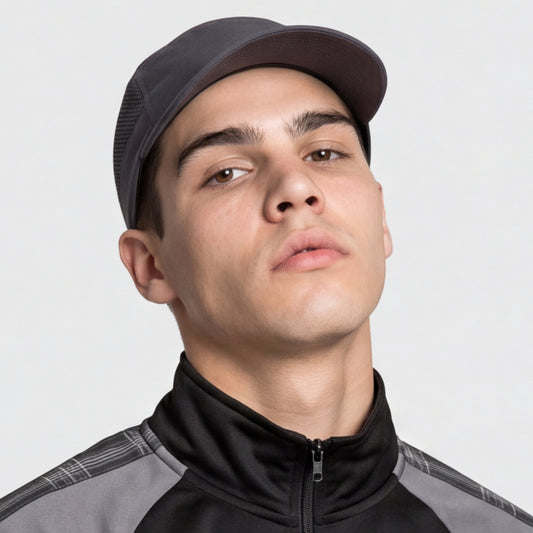Man wearing a black running light weight cap and black jacket on a light gray background