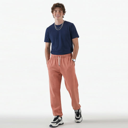 Person wearing a navy t-shirt and pink jogger pants on a white background