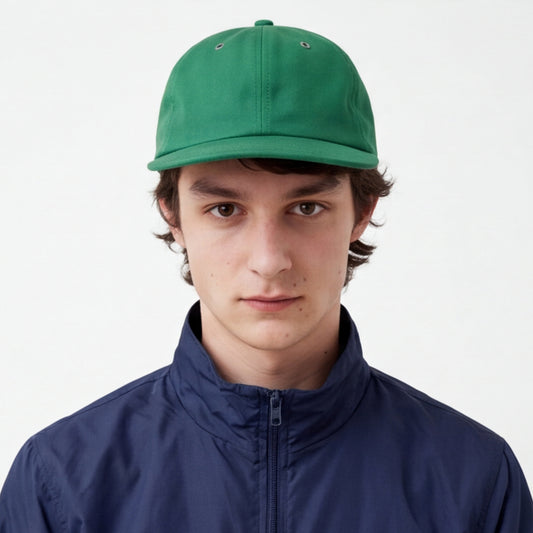 Person wearing a green unstructured flat visor cap and blue jacket on a white background