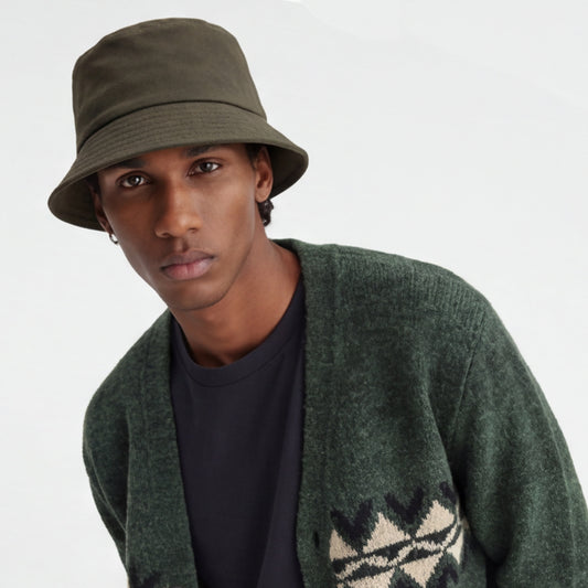 Man wearing a green bucket hat and cardigan with a white background