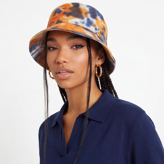 Woman wearing a tie-dye bucket hat and blue shirt on a white background