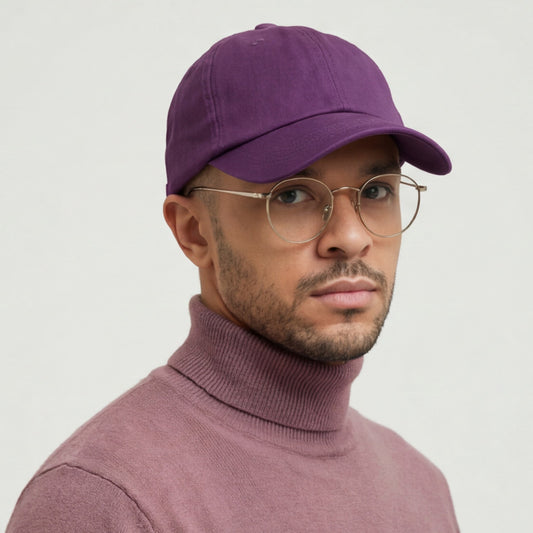 Man wearing a purple dad hat cap and turtleneck sweater against a light gray background