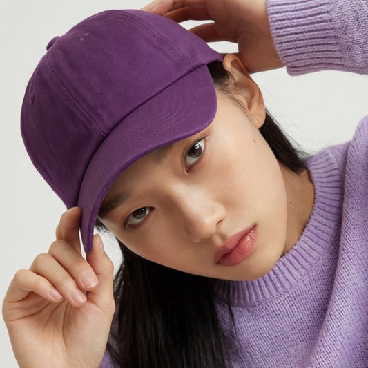 Person wearing a purple dad hat cap and sweater against a light background