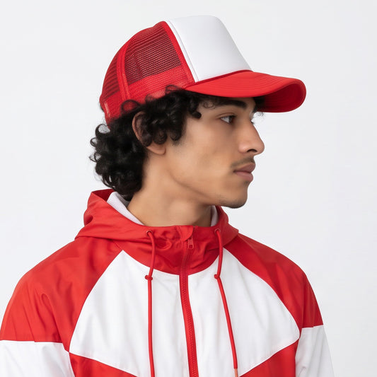 Person wearing a red and white jacket and foam trucker cap on a light gray background